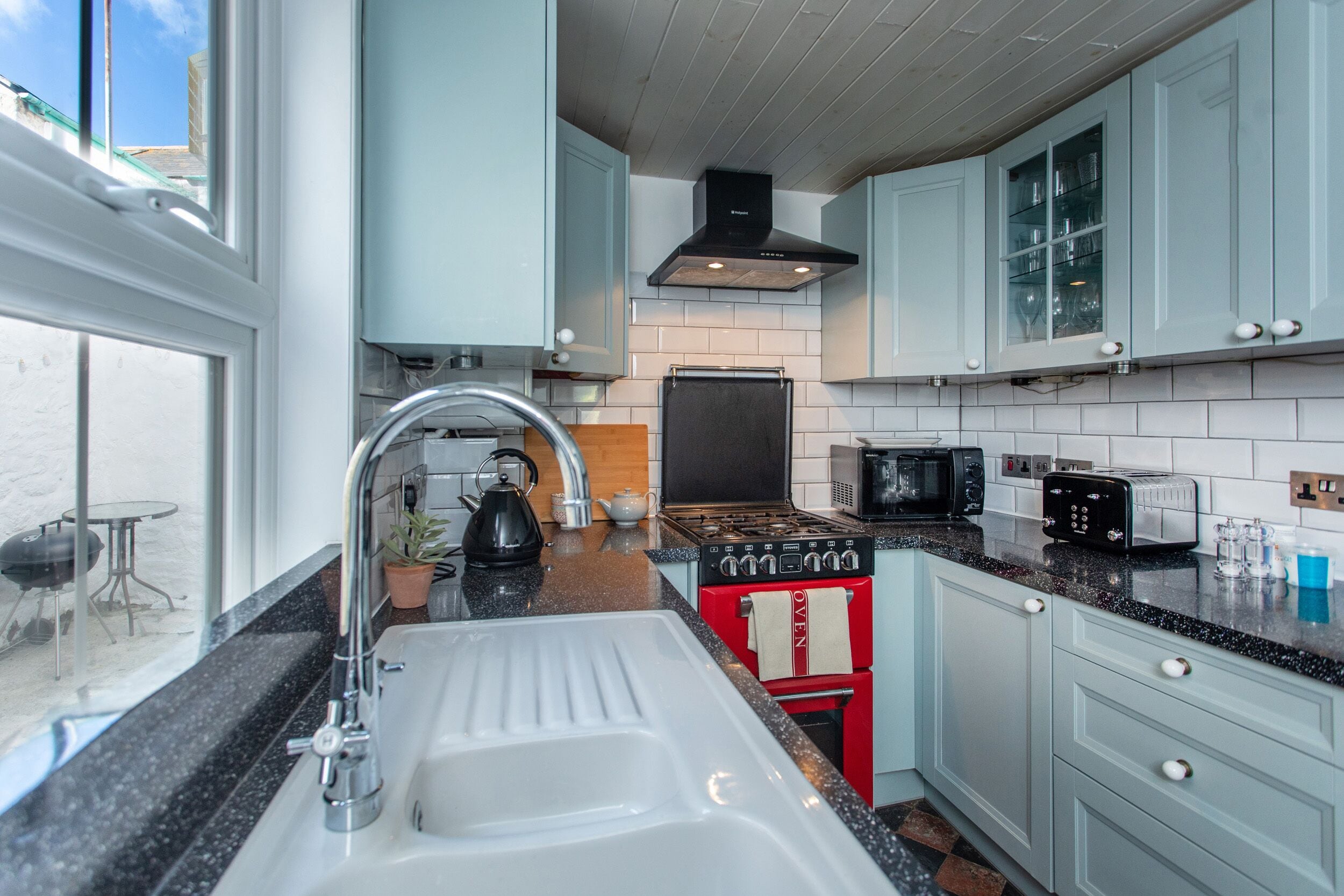 Een moderne keuken met een spoelbak, fornuis, magnetron en kastjes.