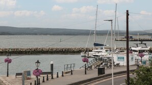 A waterfront marina with boats docked, a pedestrian walkway, and a view of the water and distant hills. - Quay Cottage - Sea View (Poole)