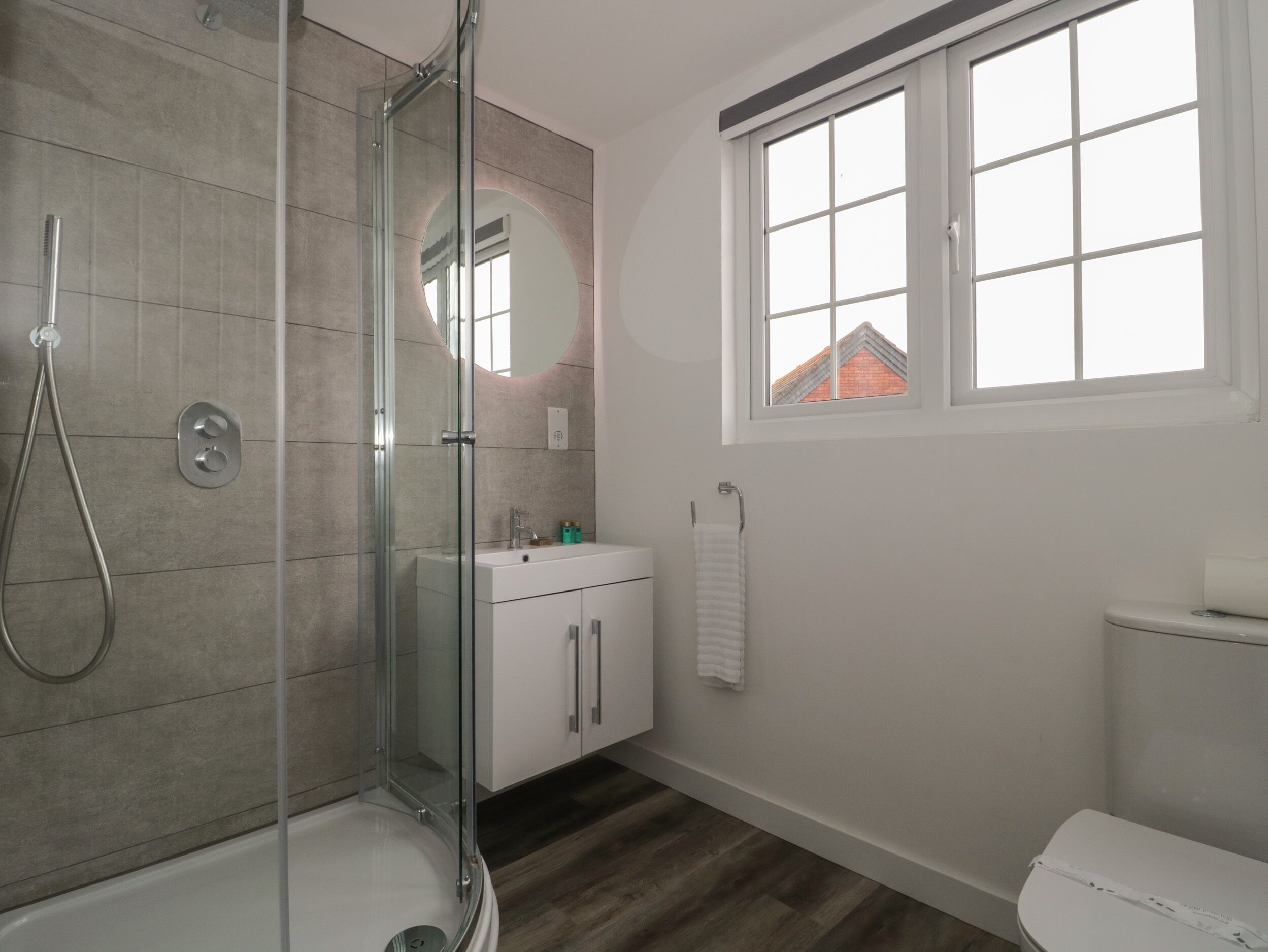 A modern bathroom with a glass-enclosed shower, a white sink, and a toilet.