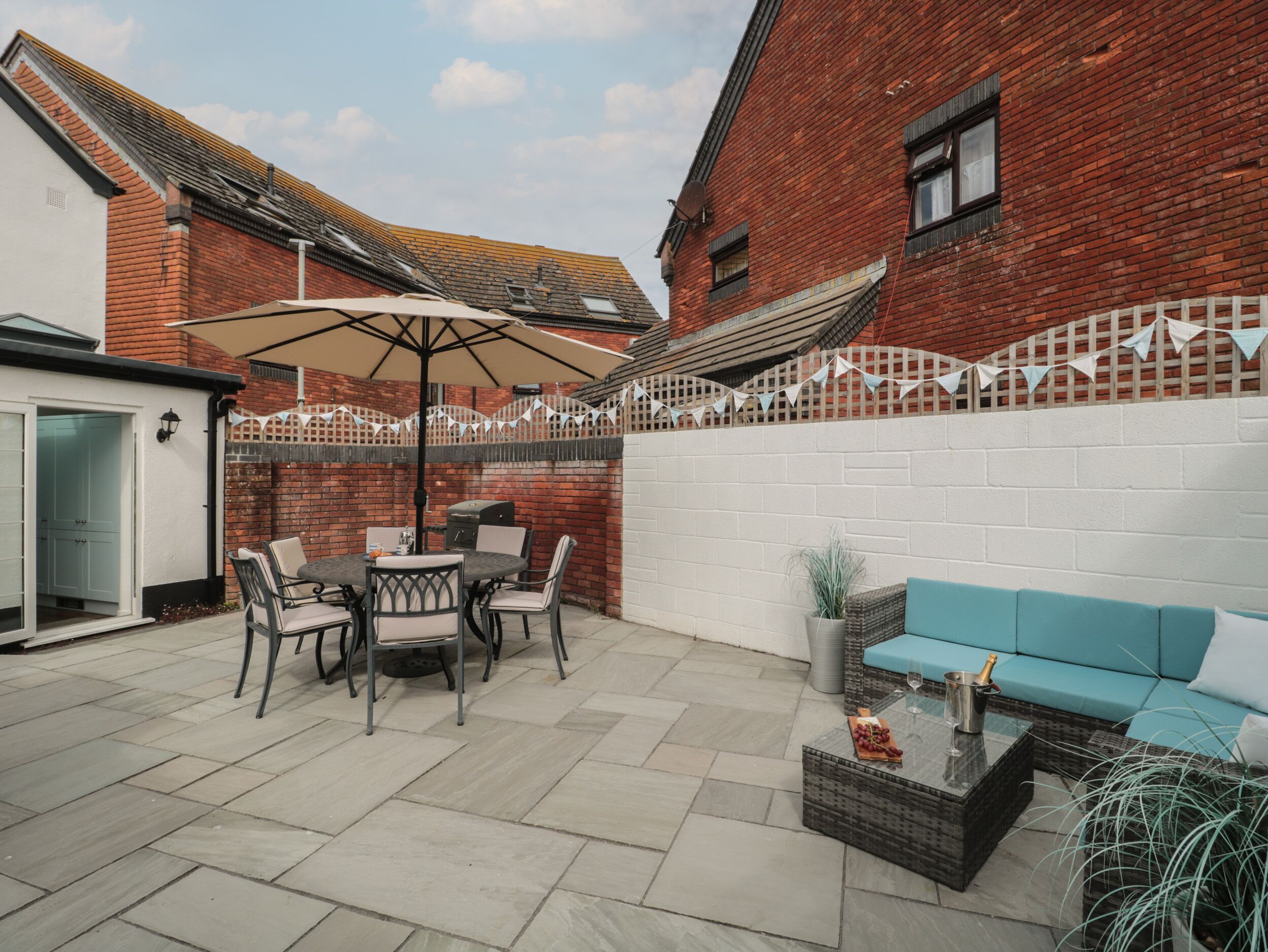 A patio with a table and chairs, a blue sofa, and a brick wall.