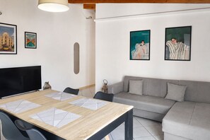 Een moderne woonkamer met een eettafel, bank en kunstwerken aan de wanden.