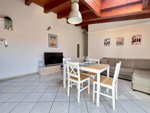 Un comedor con una mesa y sillas de madera, un televisor y un sofá.