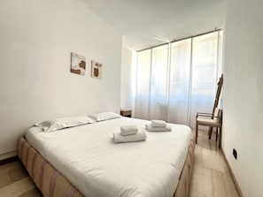 A clean, modern hotel room with a large bed, a chair, and artwork on the wall.