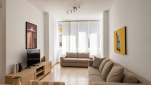 A modern living room with a sofa, a TV, and a wooden coffee table.