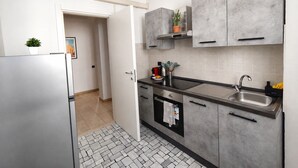 A modern kitchen with grey cabinets, a stainless steel sink, and a tiled backsplash.