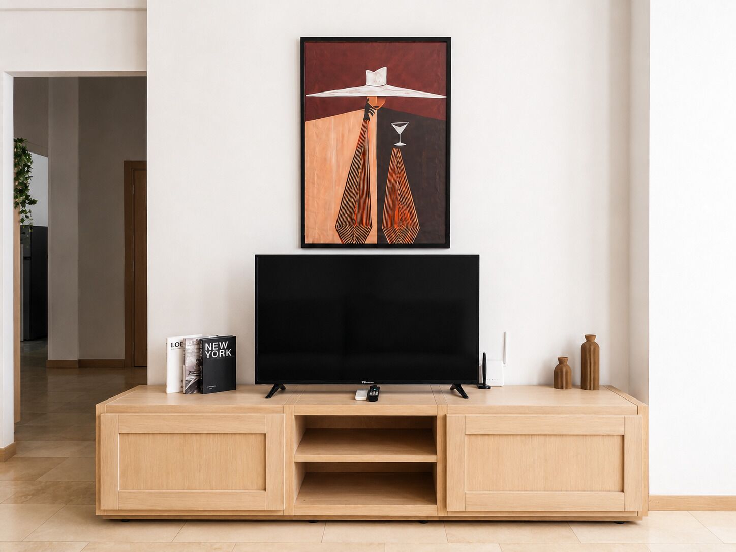 Een moderne woonkamer met een flatscreen televisie op een houten tv-meubel, een ingelijst abstract kunstwerk erboven en een afstandsbediening op het meubel.