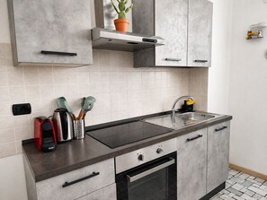 A modern kitchen with a built-in oven, stainless steel sink, and grey cabinetry.