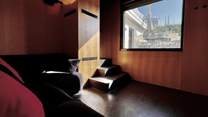 Ein modernes Interieur mit einer Holzwand, einer Couch, einem Fenster mit Blick auf ein Gebäude und einer Treppe.