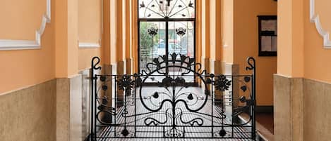A corridor with a tiled floor, a decorative gate, and a hanging light fixture.