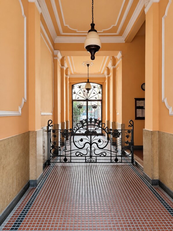 A corridor with a tiled floor, a decorative gate, and a hanging light fixture.