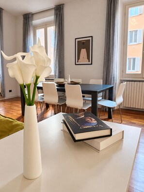 A modern dining area with a table, chairs, and a vase of white flowers.