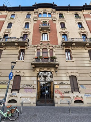 A multi-story building with ornate architectural details, including decorative balconies and a central entrance with a wrought iron gate.