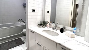 Un baño moderno con una bañera, un lavabo y un espejo grande.