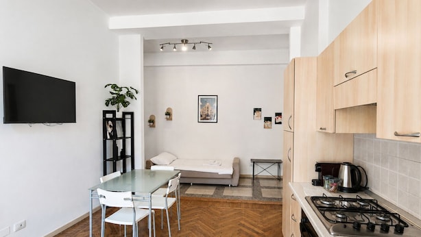 Une cuisine moderne avec un coin repas, un téléviseur à écran plat fixé au mur et un parquet en bois disposé en motif chevrons.
