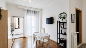 Une cuisine moderne avec un coin repas, un téléviseur à écran plat et une plante en pot.