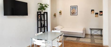 Una sala de estar moderna con una mesa de comedor, sillas, un sofá, un televisor y obras de arte en las paredes.