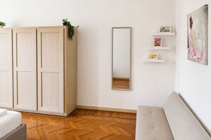Una habitación con armario, espejo, sofá y una pared con estanterías.