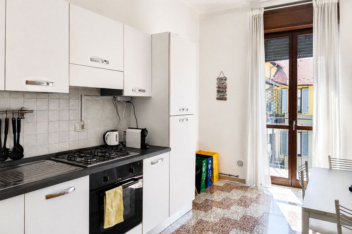 A kitchen with white cabinets, a gas stove, a coffee maker, and a refrigerator.
