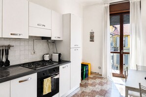 A kitchen with white cabinets, a gas stove, a coffee maker, and a refrigerator. - BIG Living Goldoni [Duomo–M4–Linate] (Milan)