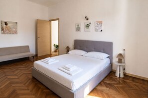 A bedroom with a bed, a bench, a door, and wall art. - BIG Living Goldoni [Duomo–M4–Linate] (Milan)