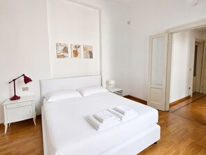 A hotel room with a bed, a nightstand, a lamp, and a wall with artwork.