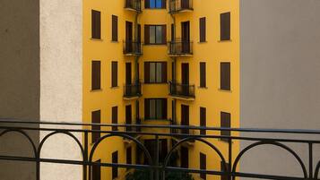 Un bâtiment jaune doté de nombreux balcons et fenêtres, vu depuis un balcon orné d’une rambarde en métal.