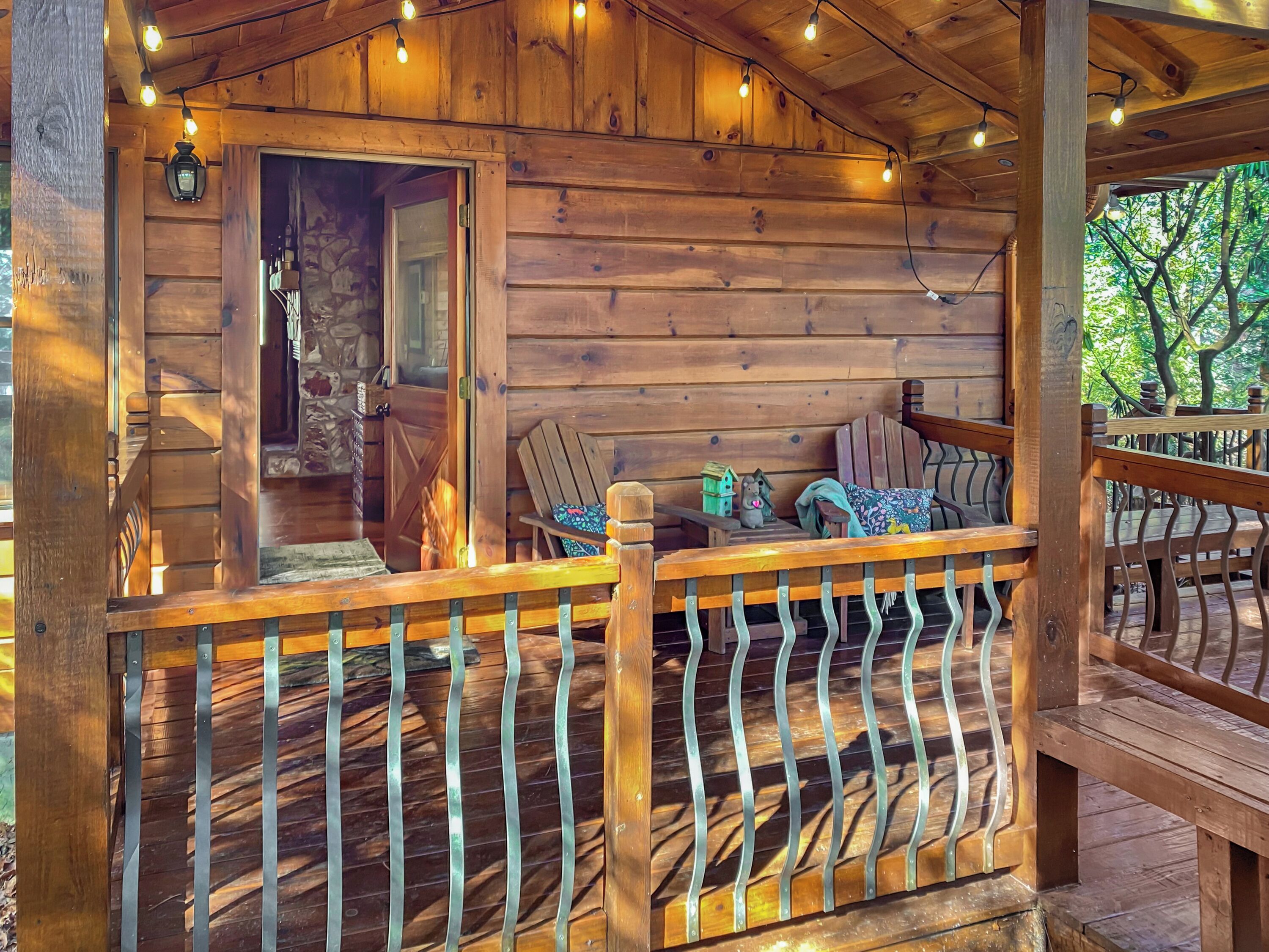 Een houten hut met een veranda, een stenen open haard en een gezellige zithoek met een bank en een stoel.