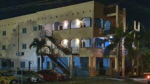 A multi-story building with a staircase leading to the upper floors, surrounded by palm trees. - Jomp Turners' Guest Apartments (Bolands)