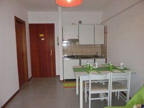 Una cocina compacta con armarios blancos, estufa a gas y una mesa de comedor con sillas.
