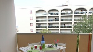 Uma varanda com uma mesa e cadeiras brancas, uma garrafa e uma xícara.