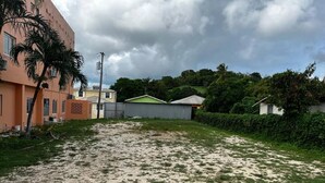Zona residenziale con un cortile sabbioso, una palma e case con tetti di diversi colori.