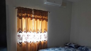Una camera da letto con un letto, tende e condizionatore d'aria.