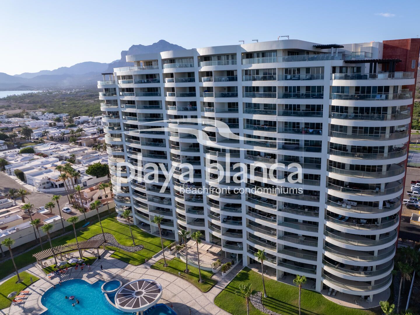 Un edificio alto con múltiples balcones, piscina y vistas del paisaje circundante.