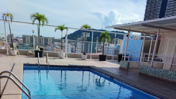 A swimming pool with a tiled edge, surrounded by a fence and potted plants. - HOTEL SAN THOMAS INN (Panama City)
