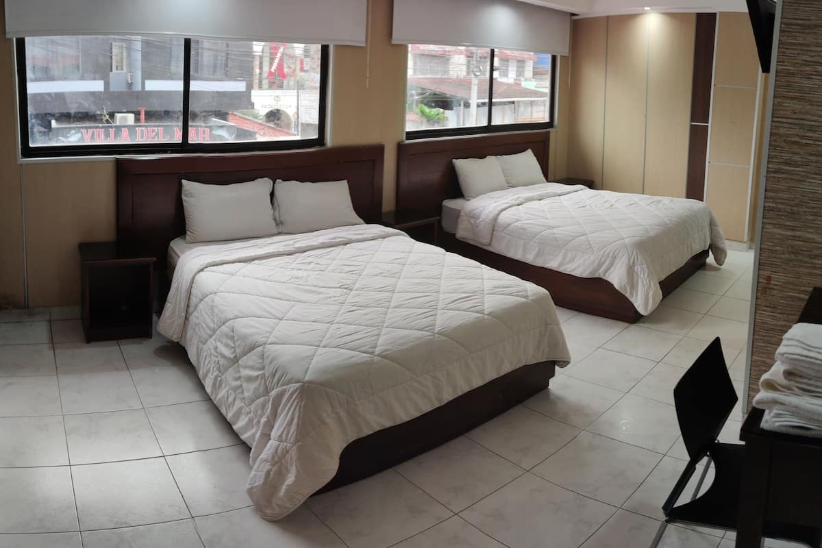 Une chambre d’hôtel avec deux lits, une fenêtre donnant sur la rue et un sol carrelé.