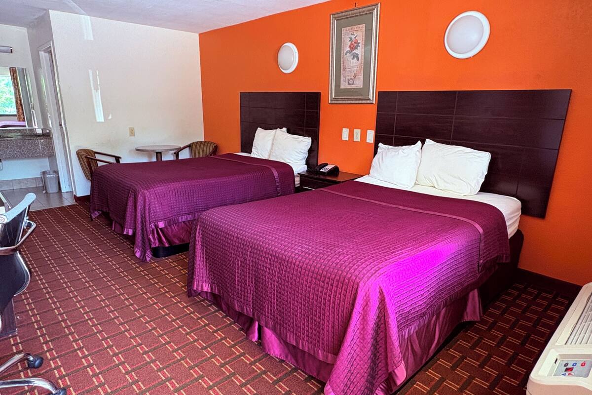 A hotel room with two beds, a desk, and a chair.
