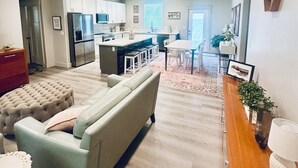 A modern living room with a grey sofa, a wooden coffee table, and a kitchen in the background. - Brand Spankin' New 4 bedroom home Sleeps 8 Pet friendly (Kimberly)