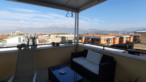 A balcony with a sofa and table, overlooking a residential area with houses and mountains in the distance. - Palazzo Di Donna Penthouse terrace view Vesuvius strategic to Pompeii, Amalfi coast (Sant'Egidio del Monte Albino)