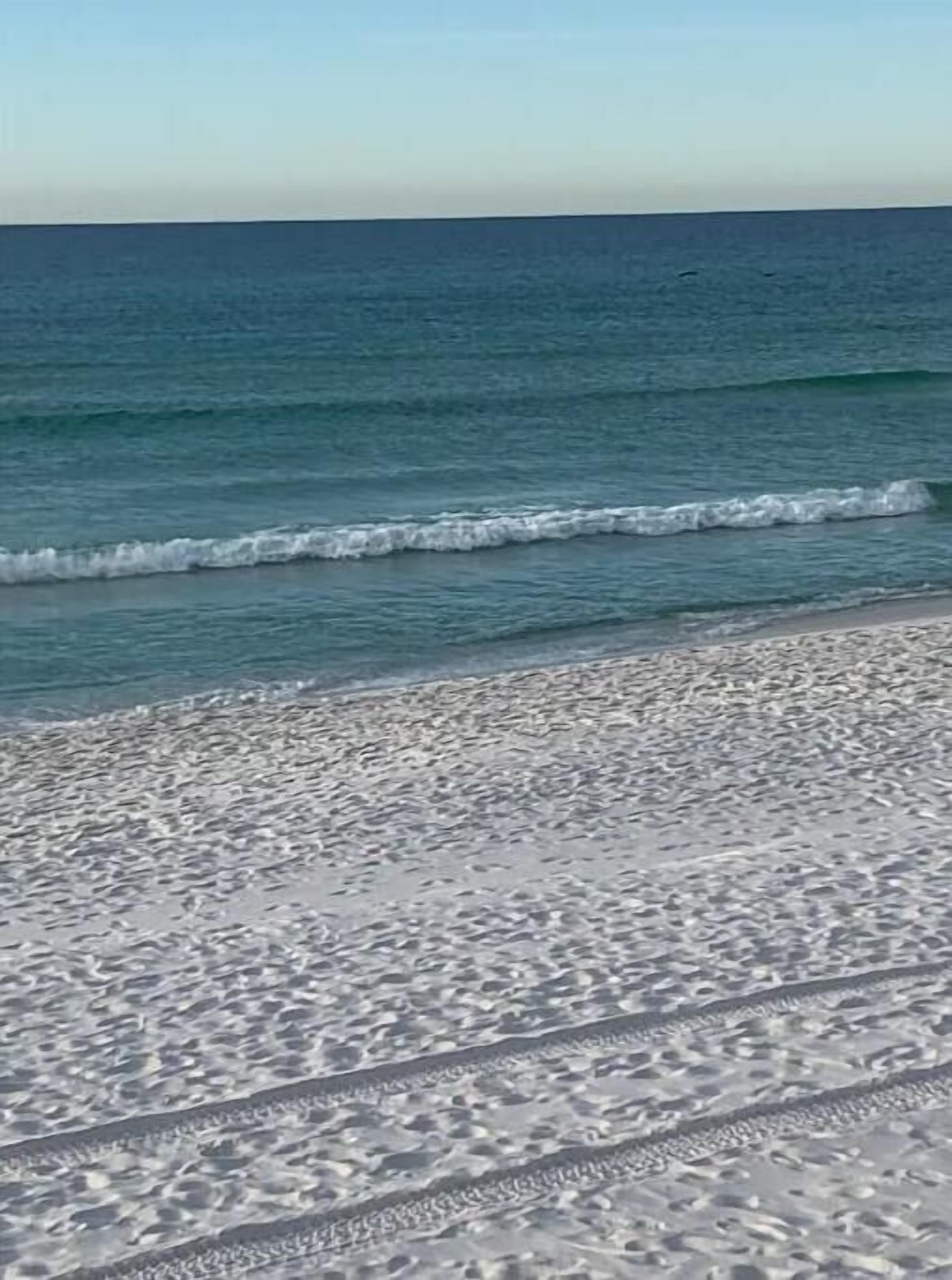 A beach with clear blue water and a sandy shore.