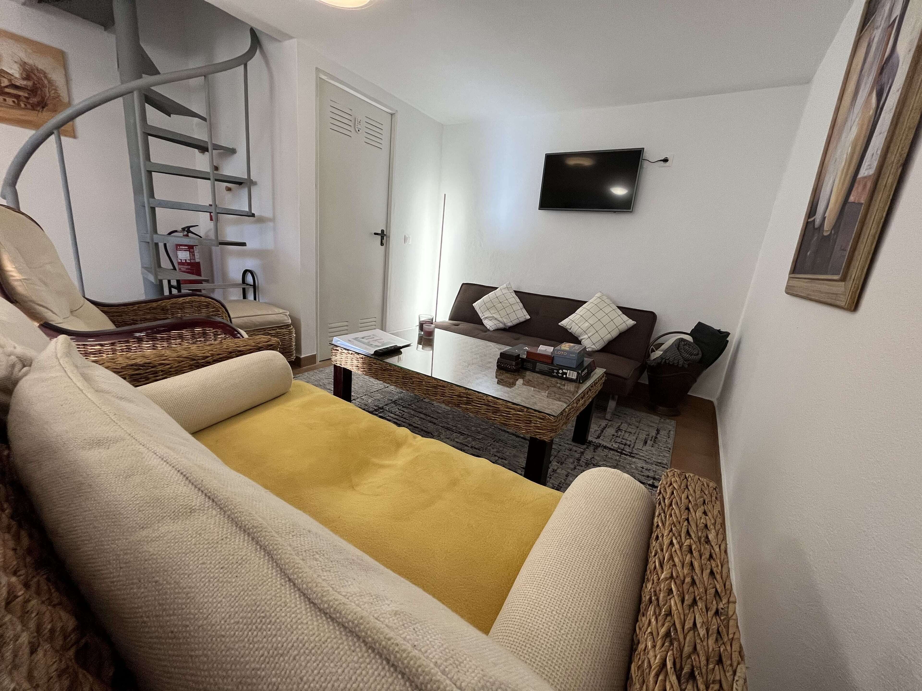 A living room with a sofa, a coffee table, a television, and a staircase.