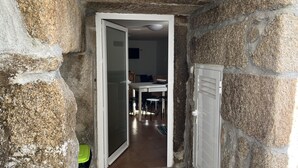 Ein enger Korridor mit Steinwänden, der zu einem Raum mit Esstisch und Stühlen führt.