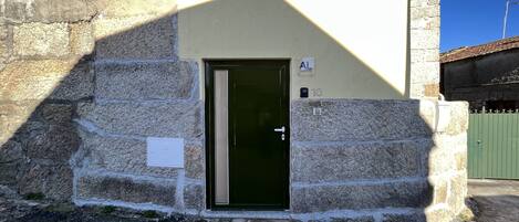 A stone building with a green door, a small sign above the door, and a number '10' on the wall.