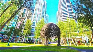 A park with a large spherical sculpture surrounded by tall buildings.