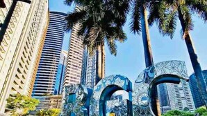 A cityscape with tall buildings and palm trees.