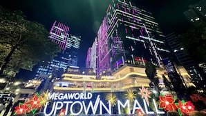 A brightly lit building with the sign "MEGAWORLD UPTOWN MALL" and decorative lights.