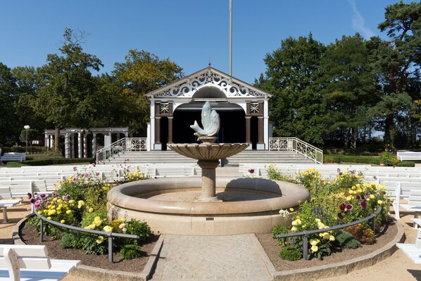 A gazebo with a central fountain, surrounded by white benches and flower beds. - Ostseeblick - Luxus in 1a-lage Mittelpromenade (Ostseebad Boltenhagen)