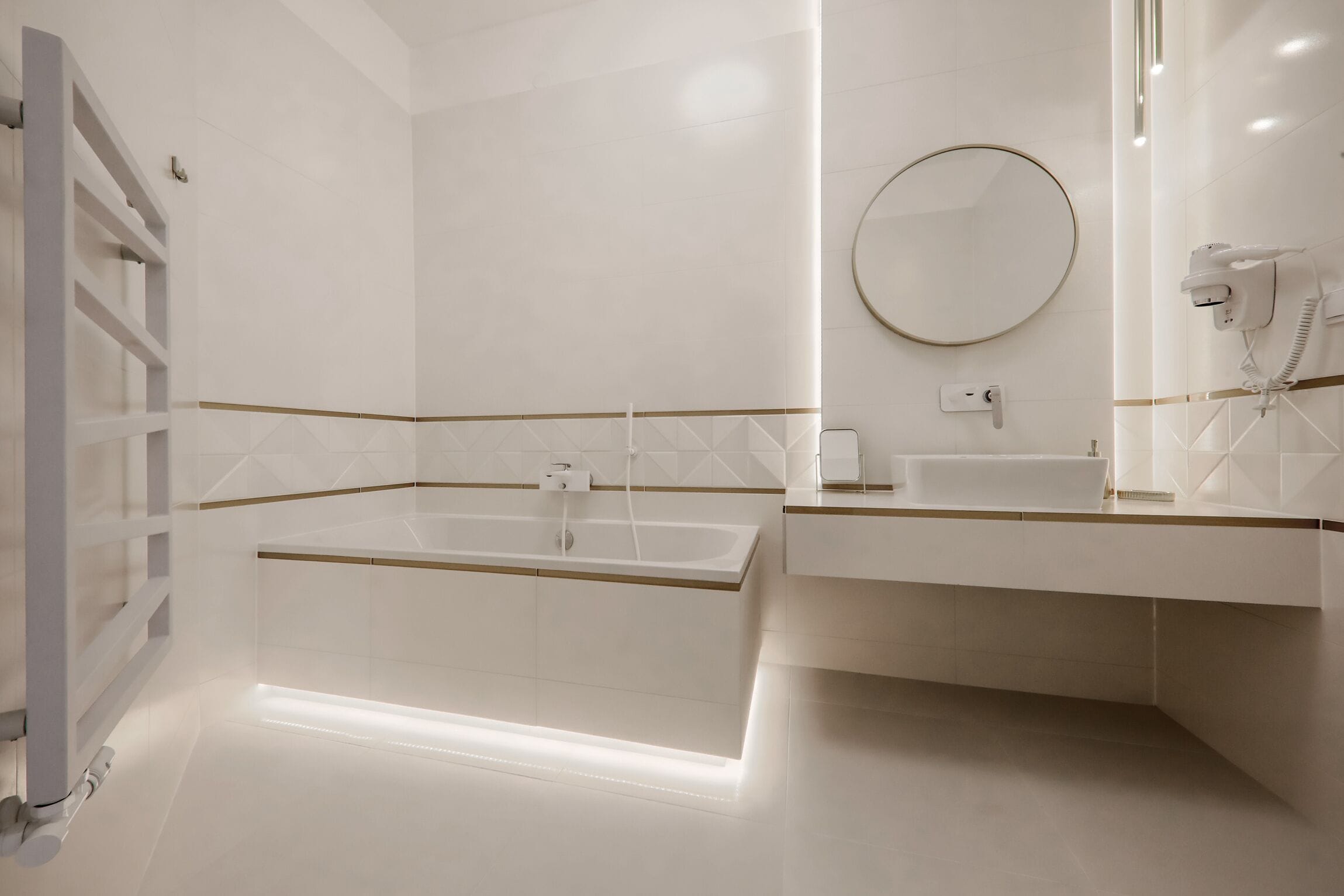 Un baño moderno con una bañera grande, un lavamanos y un secador de pelo.