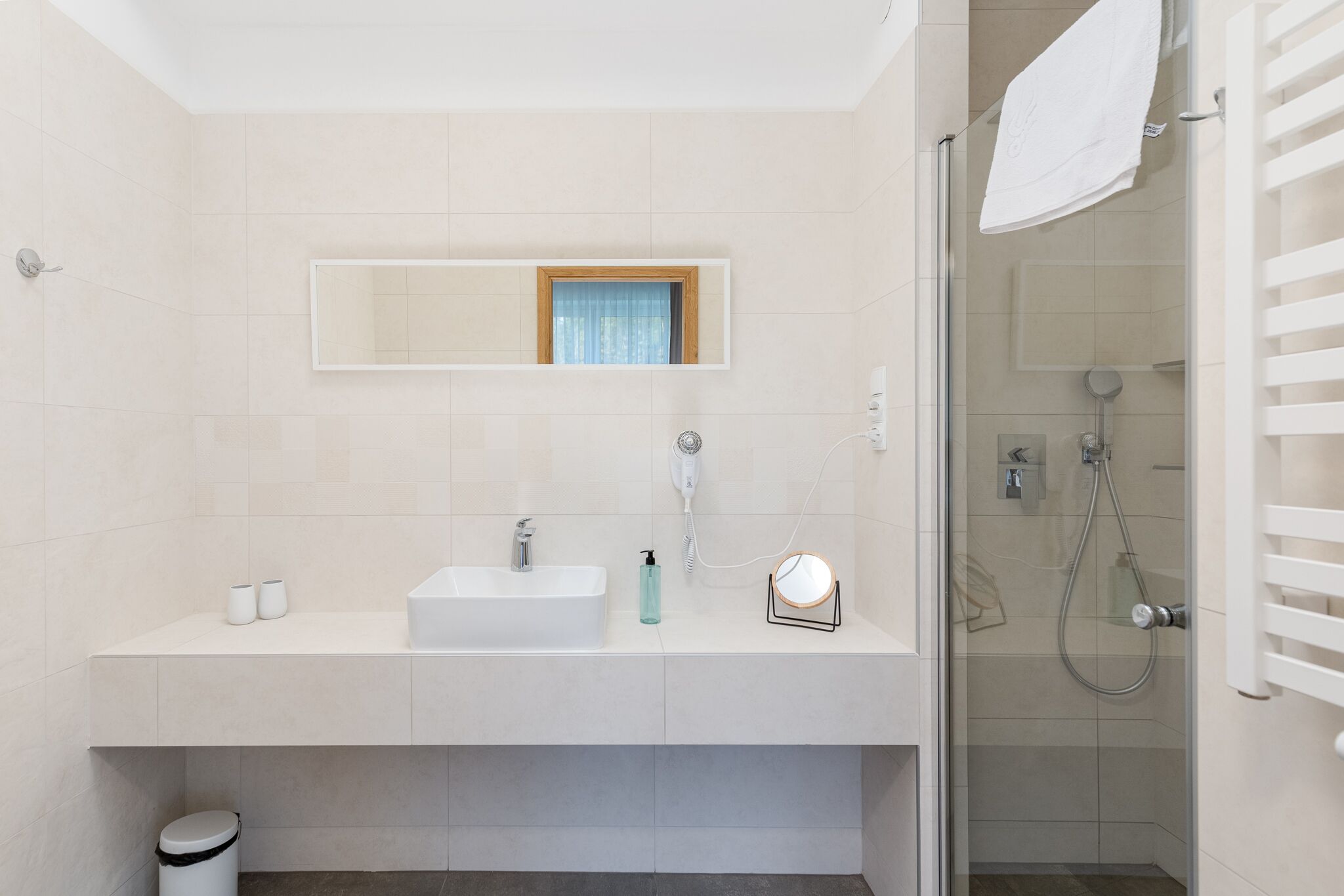 Un baño moderno con lavamanos, espejo y ducha.