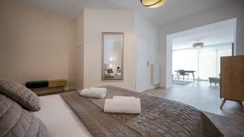 Una habitación de hotel moderna con una cama grande, un espejo y vistas al comedor.