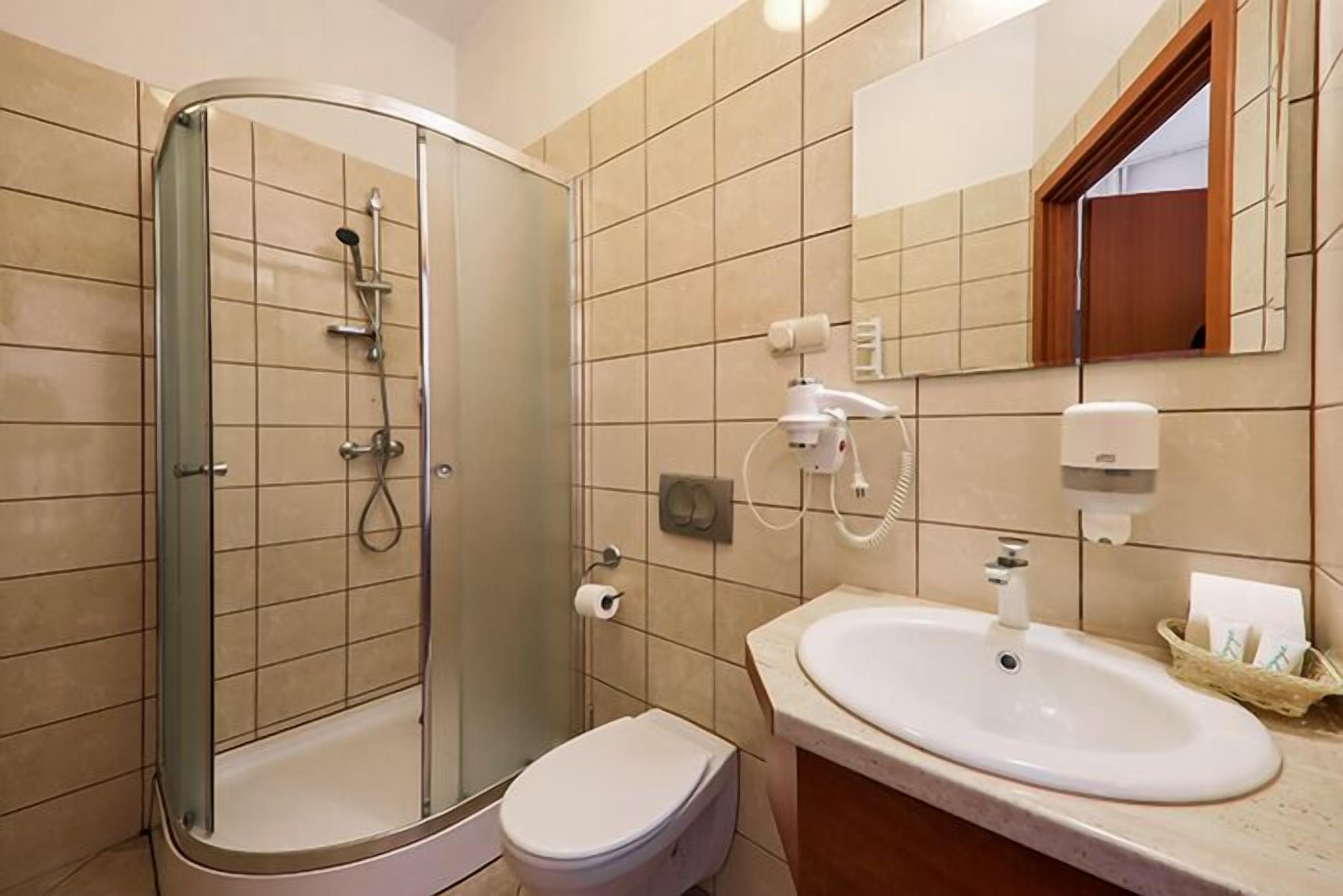 Un baño moderno con ducha envuelta en vidrio, un lavamanos blanco y un inodoro.